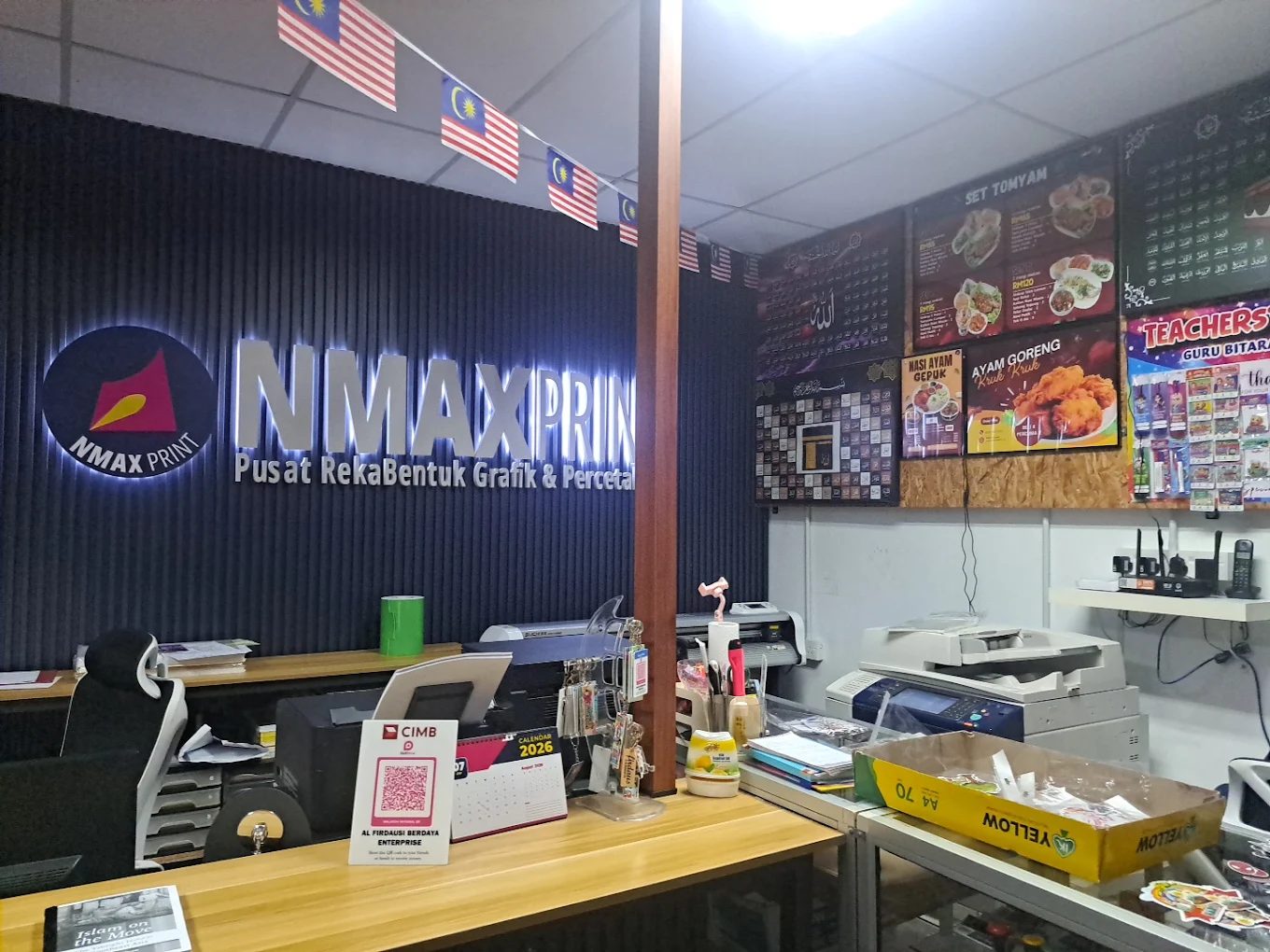 Kaunter pelanggan NMAX Print dengan contoh menu board dan papan tanda